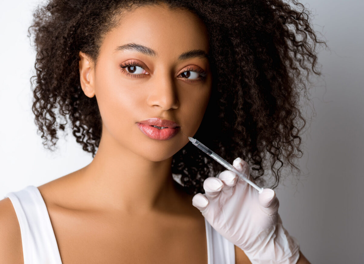 young african american woman making beauty injection, isolated on grey